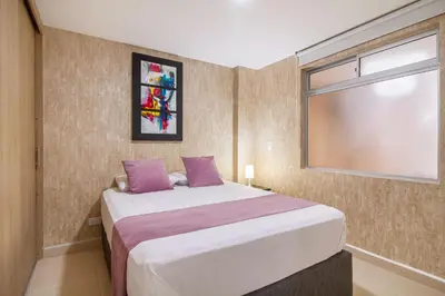 a bedroom with a bed with purple pillows and a window at Hermoso apartamento en el centro in Medellín