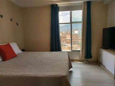 a bedroom with a bed and a large window at Lovely one bedroom condo in beautiful Laureles in Medellín