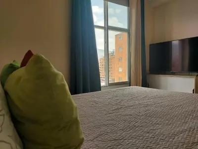 a bedroom with a bed with a large window at Lovely one bedroom condo in beautiful Laureles in Medellín