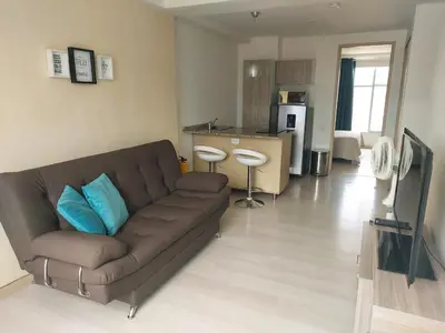 a living room with a brown couch and a kitchen at Lovely one bedroom condo in beautiful Laureles in Medellín