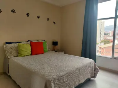 a bedroom with a bed with colorful pillows and a window at Lovely one bedroom condo in beautiful Laureles in Medellín