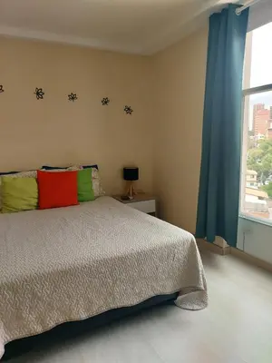 a bedroom with a bed with colorful pillows and a window at Lovely one bedroom condo in beautiful Laureles in Medellín