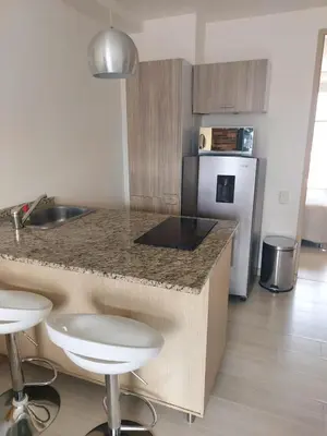 a kitchen with a counter with stools and a refrigerator at Lovely one bedroom condo in beautiful Laureles in Medellín