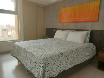 a bedroom with a large bed with a checkered blanket at Laureles Deluxe Apartment in the Medellin sky in Medellín