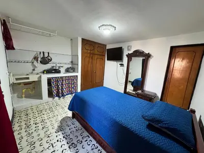 a bedroom with a blue bed and a kitchen at Aparta estudio comuna trece in Medellín