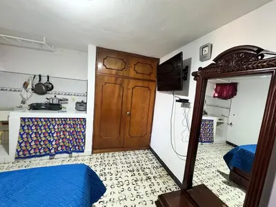 a bedroom with a bed and a kitchen and a door at Aparta estudio comuna trece in Medellín