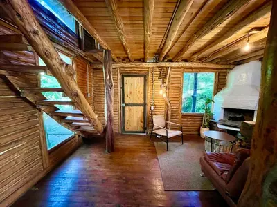 a living room with a staircase in a log cabin at Forest Cabin Nature Retreat in Rionegro