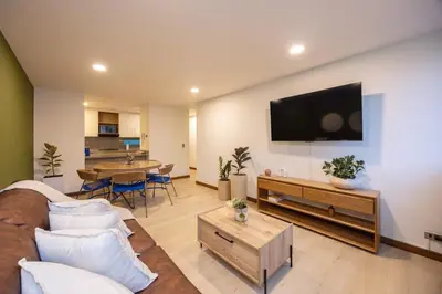 a living room with a couch and a tv on a wall at Cómodo y recién remodelado apto de 2 habitaciones cerca a Provenza in Medellín