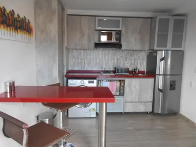a kitchen with a red counter top and a refrigerator at Laureles 16th floor stylish Spring City Treat in Medellín