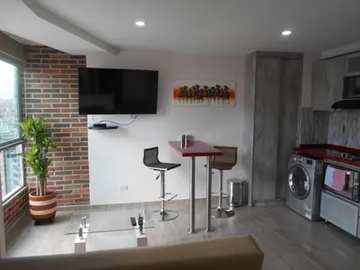 a living room with a table and a tv on the wall at Laureles 16th floor stylish Spring City Treat in Medellín
