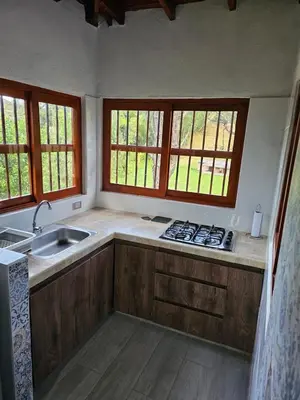 a kitchen with wooden cabinets and a sink and windows at Don tranquilo in Concepción