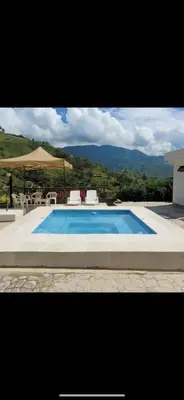 a large swimming pool with chairs and an umbrella at FINCA LA MIEL en Barbosa Antioquia in Barbosa