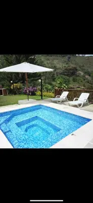 a swimming pool with an umbrella and two chairs and a table and an umbrella at FINCA LA MIEL en Barbosa Antioquia in Barbosa