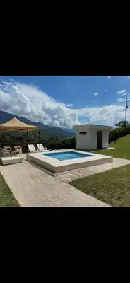 a swimming pool with chairs and an umbrella next to a house at FINCA LA MIEL en Barbosa Antioquia in Barbosa