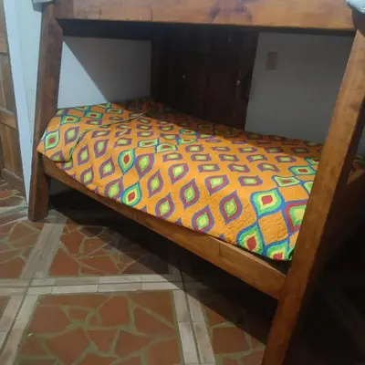 a small wooden bed with a colorful comforter on it at HOSTAL - COLIVING - Cerca MetroCable ARVI in Guarne