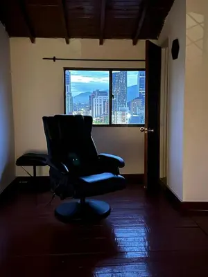 a chair sitting in a room with a window at Apto con vista en distrito cultural de Medellín in Medellín