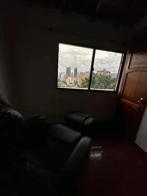 a dark room with a chair and a window at Apto con vista en distrito cultural de Medellín in Medellín