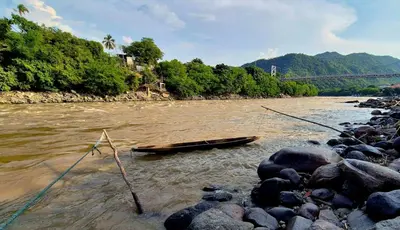 a boat on a river with rocks and a bridge at Casa de pesca in Honda