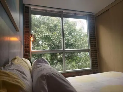 a bedroom with a bed and a large window at Stylish Laureles Loft in Medellin in Medellín