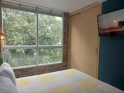 a bedroom with a bed and a large window at Stylish Laureles Loft in Medellin in Medellín