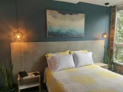 a bedroom with a bed and a painting on the wall at Stylish Laureles Loft in Medellin in Medellín