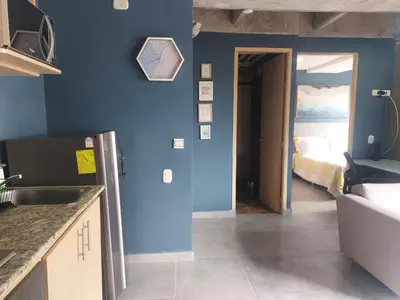 a kitchen with a blue wall and a bedroom at Stylish Laureles Loft in Medellin in Medellín