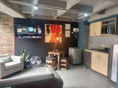 a living room with a couch and a kitchen at Stylish Laureles Loft in Medellin in Medellín
