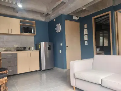 a living room with a white couch and a refrigerator at Stylish Laureles Loft in Medellin in Medellín
