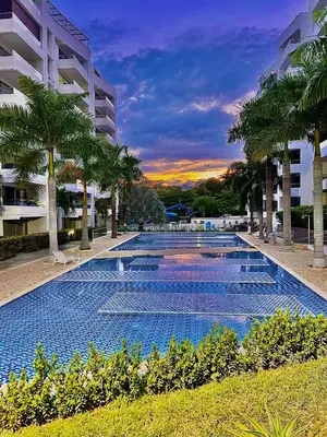 a large swimming pool with palm trees in front of a building at Encantador alojamiento en San Jerónimo in San Jerónimo