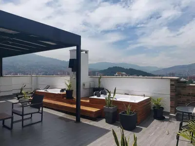 a rooftop patio with a hot tub and table and chairs at Laureles penthouse, jacuzzi-rooftop fun in the sun in Medellín