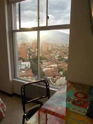 a view of a city from a window with a chair at Laureles penthouse, jacuzzi-rooftop fun in the sun in Medellín
