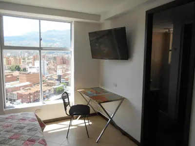 a bedroom with a desk and a tv and a window at Laureles penthouse, jacuzzi-rooftop fun in the sun in Medellín