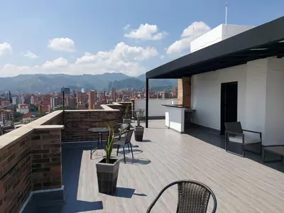 a rooftop patio with tables and chairs on a building at Laureles penthouse, jacuzzi-rooftop fun in the sun in Medellín