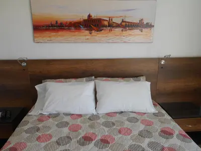 a bedroom with a bed with two pillows and a painting at Laureles penthouse, jacuzzi-rooftop fun in the sun in Medellín