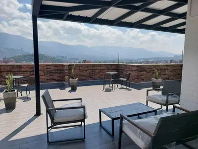 a patio with chairs and tables on a roof at Laureles penthouse, jacuzzi-rooftop fun in the sun in Medellín