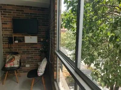 a living room with a window and a television at Medellin, Bring your toothbrush, in Laureles in Medellín