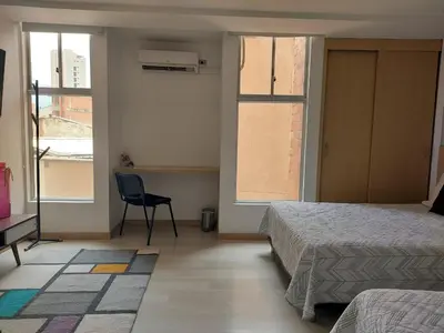 a bedroom with two beds and a desk and two windows at Medellin, Bring your toothbrush, in Laureles in Medellín