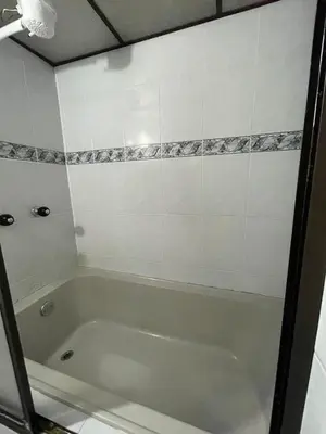 a bath tub in a bathroom with a tile wall at Hotel boutique san pablo H5 in Medellín