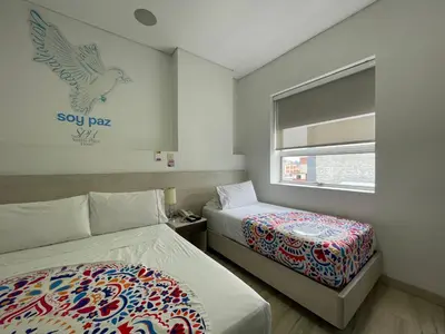 a hotel room with two beds and a window at Hotel Sixtina Plaza Medellin in Medellín