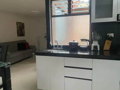a kitchen with a counter top and a living room at Apartamento renovado parque La Floresta, reserva minimo de 21 dias in Medellín