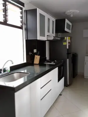 a kitchen with white cabinets and a black counter top at Apartamento renovado parque La Floresta, reserva minimo de 21 dias in Medellín