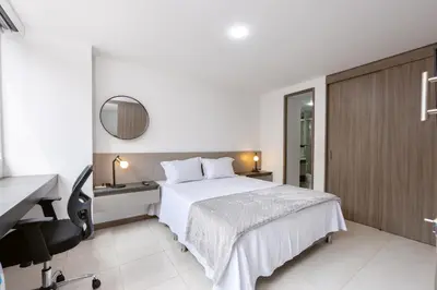 a bedroom with a bed and a desk and a mirror at Mirador Verde by MOME in Medellín