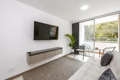 a living room with a white couch and a tv at Mirador Verde by MOME in Medellín