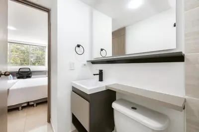 a bathroom with a sink and a toilet and a bed at Mirador Verde by MOME in Medellín