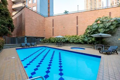 a large blue swimming pool next to a brick building at Magnífico apartamento de 2 habitaciones con AC y vistas en Provenza in Medellín