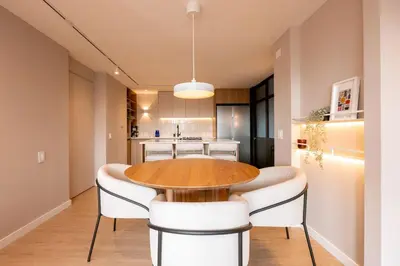 a kitchen and dining room with a wooden table and white chairs at Magnífico apartamento de 2 habitaciones con AC y vistas en Provenza in Medellín