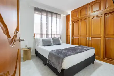 a bedroom with a bed with wooden cabinets and a window at Parque de Envigado a 350 mts, 2bd, 500mb internet in Envigado