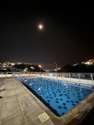 a swimming pool at night with the moon overhead at Acogedor y moderno apartamento en Manizales in Manizales