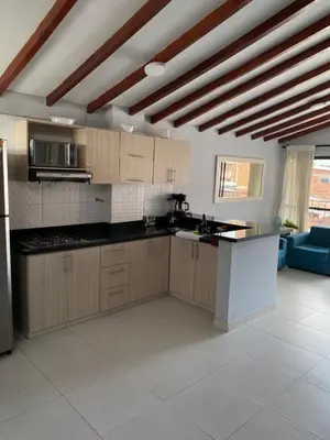 a large kitchen with wooden cabinets and a blue couch at Apartamento cerca al metro y viva envigado in Itagüí