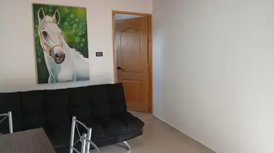 a living room with a black couch and a picture of a horse at Chalet los naranjos in La Pradera